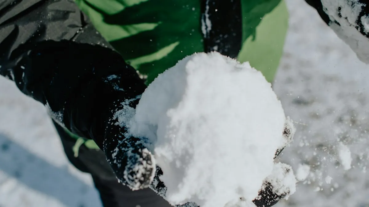 Des mains gantées tiennent une grosse boule de neige